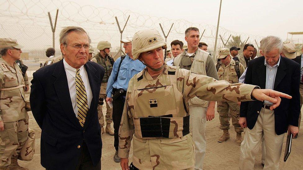 Secretary of Defense Donald Rumsfeld (L) is briefed about detainee operations by Major General Geoffry Miller (2nd L), the Deputy Director of Detainee Operations for Iraq while touring the Abu Ghraib Prison Facility May 13, 2004 outside Baghdad, Iraq