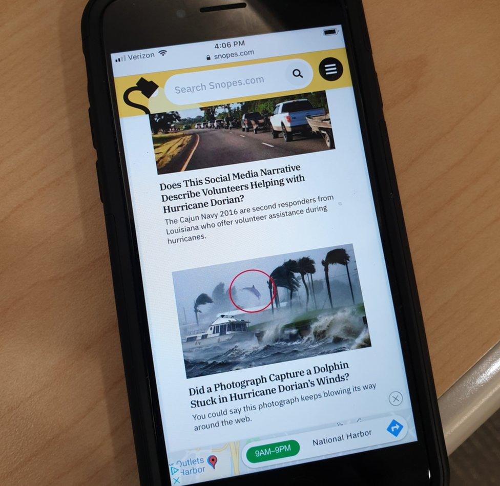 A photograph of the Snopes website on a phone highlight two stories asking about Hurricane Dorian