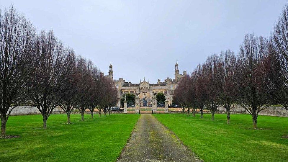 Stone-built stately home at the end of a tree-lined avenue