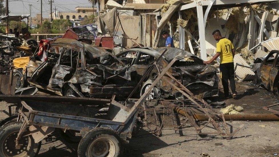 Civilians inspect the scene of the deadly suicide car bombing on Friday night at a busy market in Khan Beni Saad (18 July 2015)