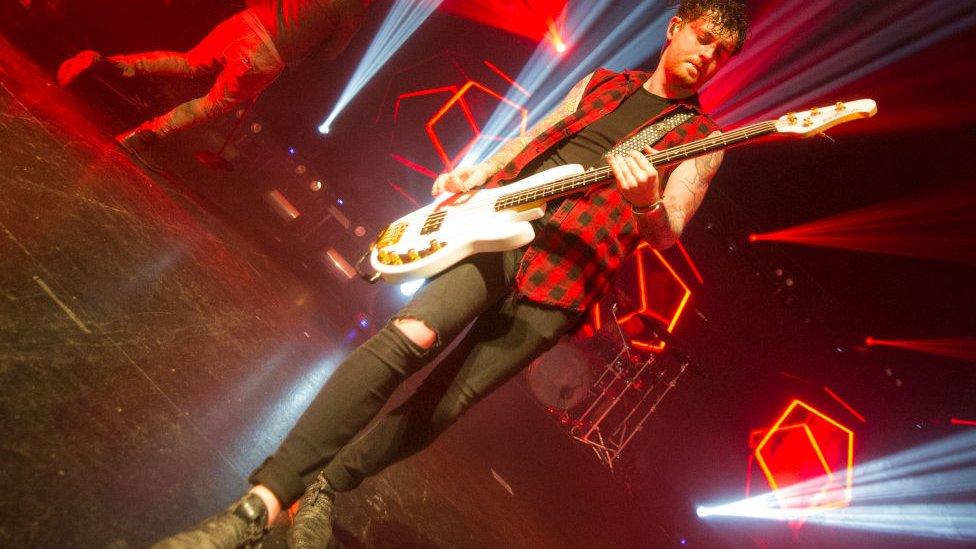 Denis Stoff, performing on stage with a guitar in 2018