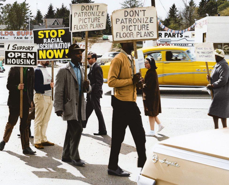 Demonstrators walk with placards