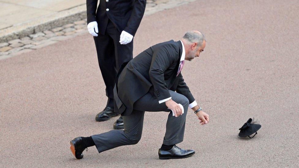 A guest chases after a hat in the wind as he arrives for the wedding of Princess Eugenie to Jack Brooksbank