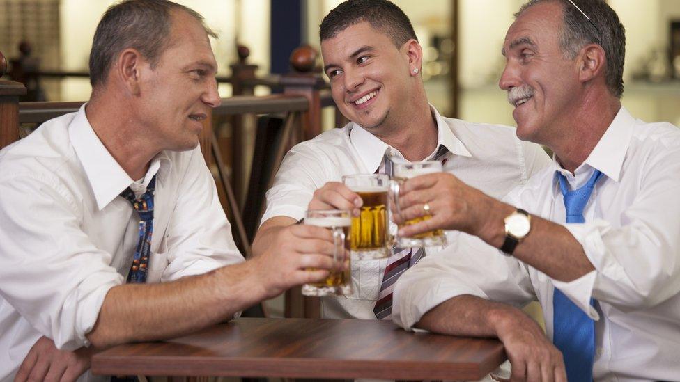 Three men drinking beer round table