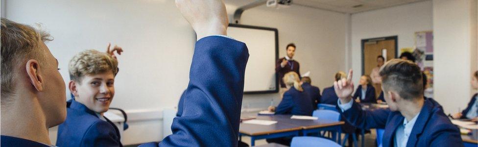 Pupils raise hand in classroom