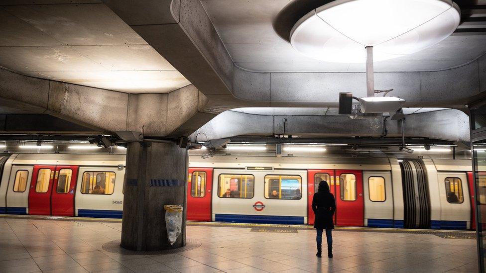 Woman stands at empty Tube station