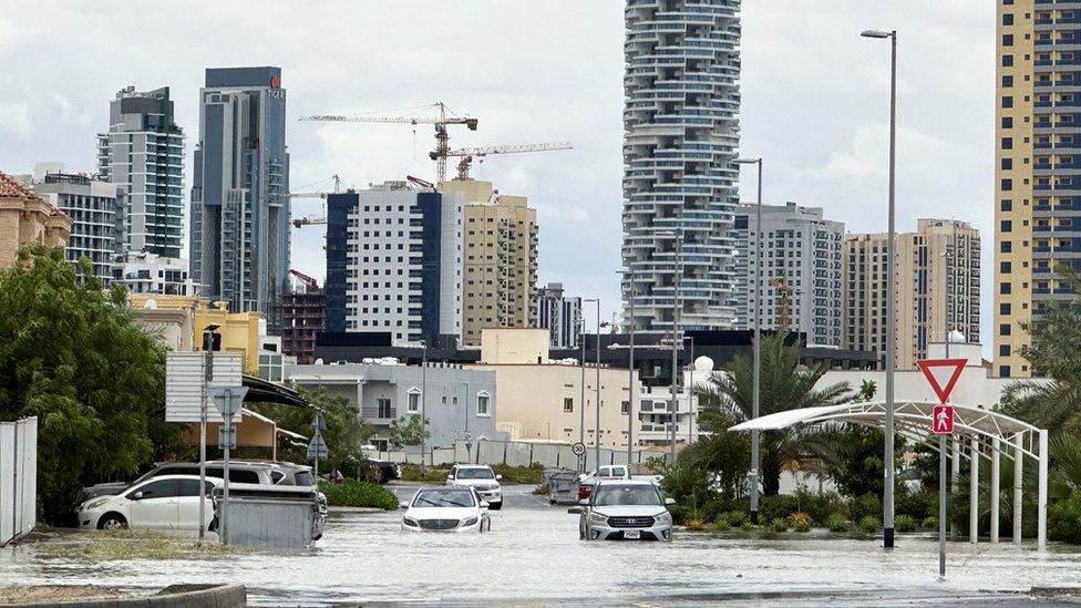 Cars drive through a flooded street during a rain storm in Dubai