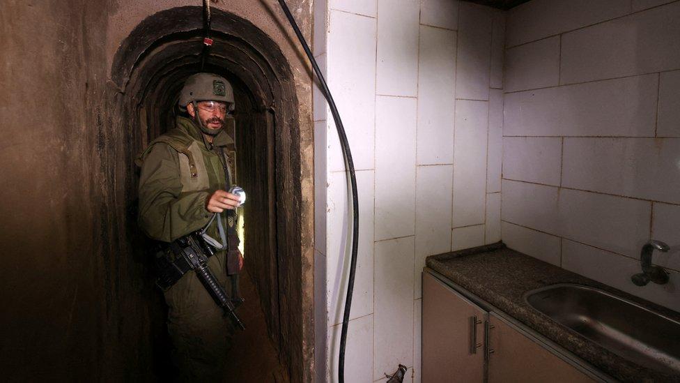 An Israeli soldier shines a torch light at a kitchen off an underground tunnel in the area of Al-Shifa Hospital, in Gaza City (22 November 2023)