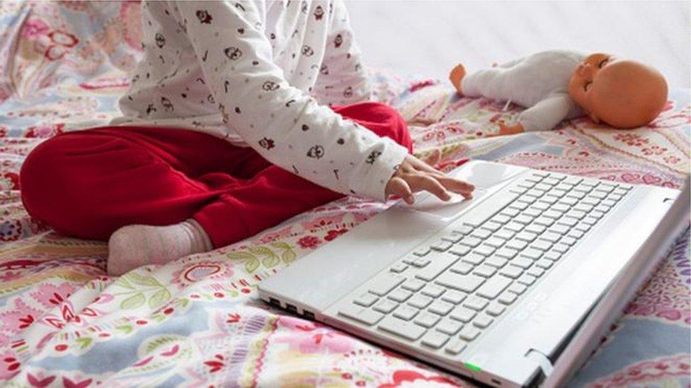 child with laptopon bed