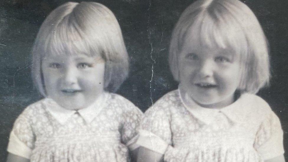 Two girls with bob haircuts wearing identical dresses