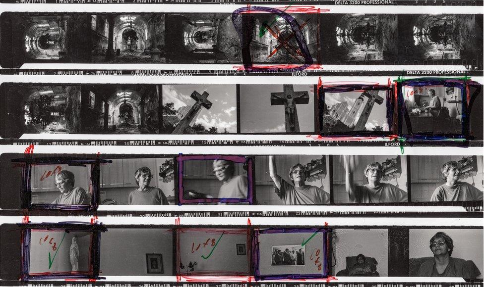 A contact sheet showing photographic negatives with red pen markings on