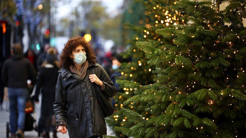 Woman in mask next to Christmas tree