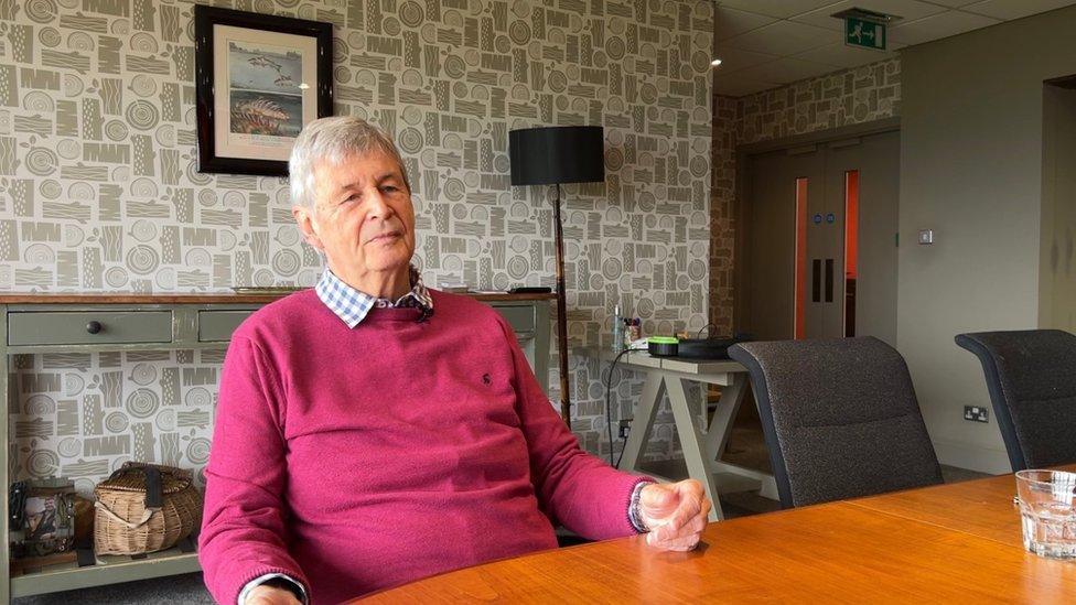 Phillip Smith, chair of Blagdon Parish Council sitting at a table wearing a shirt and jumper