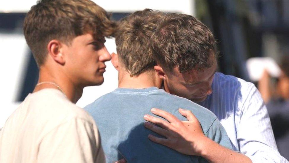 A group of men consoling each other outside a vigil in Nottingham.