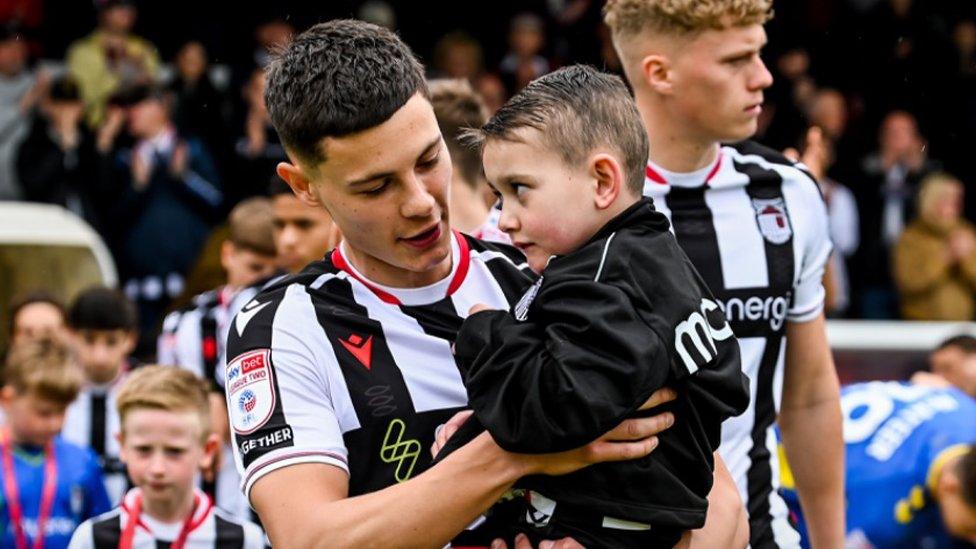 Mariners midfielder Alex Hunt carrying Reggie onto the pitch