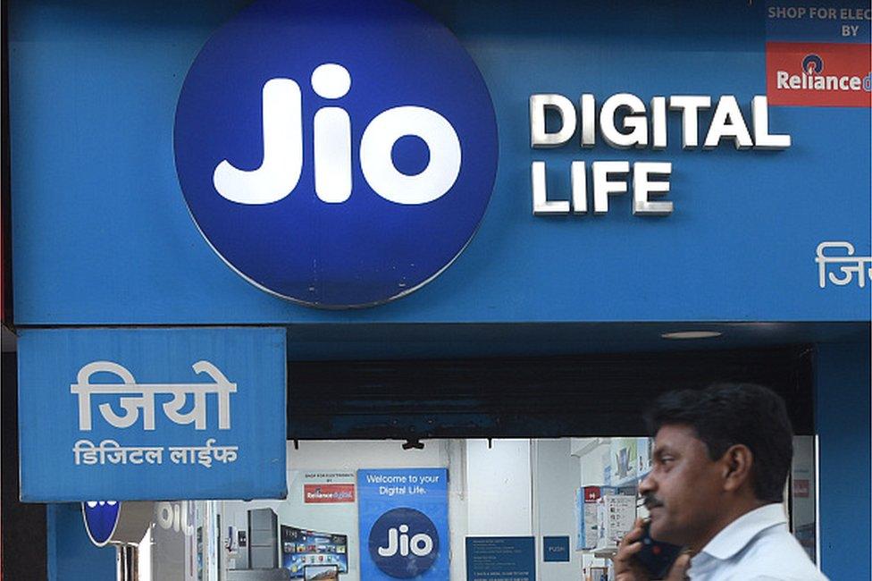 A man talks on his phone walks past a Jio store in Mumbai, India, 22 March, 2023.