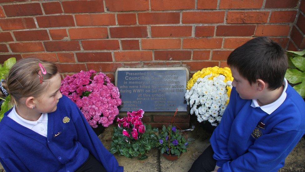 Two pupils looking at a commemorative plaque at a school