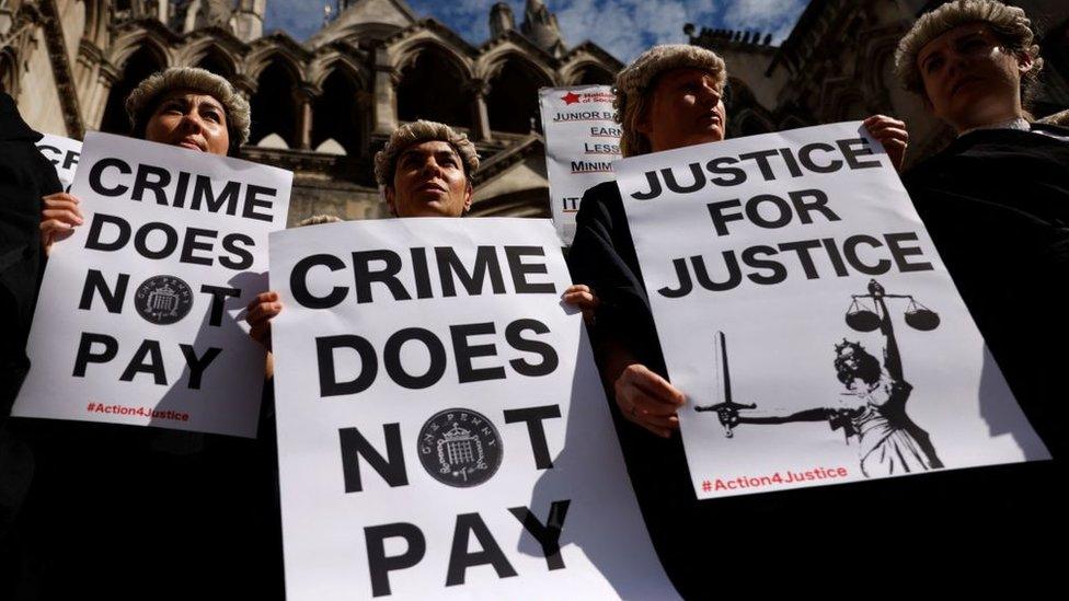 Senior criminal lawyers hold placards outside the Royal Courts of Justice in London on July 4, 2022 as they go on strike in a dispute over pay.