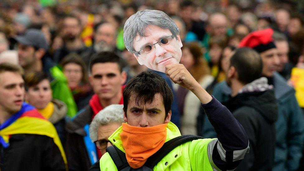 A protester holds a mask of Catalonia's former president Carles Puigdemont during a demonstration in Barcelona on 25 March 2018