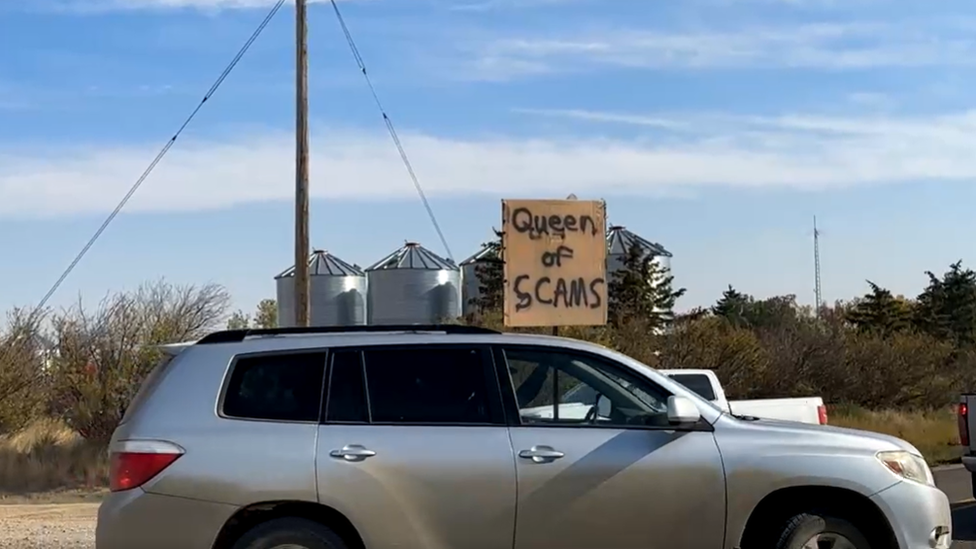 Part of Sunday's protest against the camp inside the school. A sign reads "Queen of Scams"