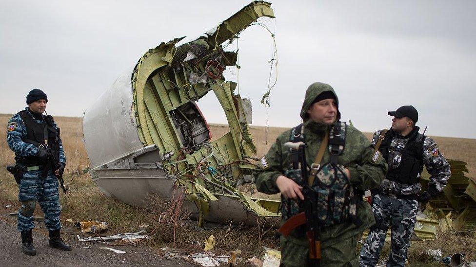 Pro-Russian gunmen stand guard as Dutch investigators (unseen) arrive near parts of the Malaysia Airlines Flight MH17 at the crash site near the Grabove village in eastern Ukraine on November 11, 2014