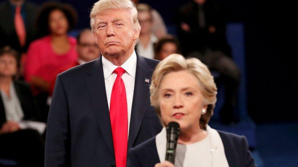 Donald Trump listens as Hillary Clinton answers a question during presidential debate at Washington University in St Louis, Missouri, U.S., October 9, 2016