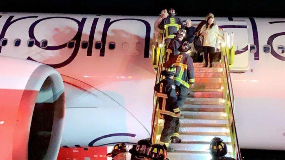 Firefighters board a Virgin Atlantic plane on the runway