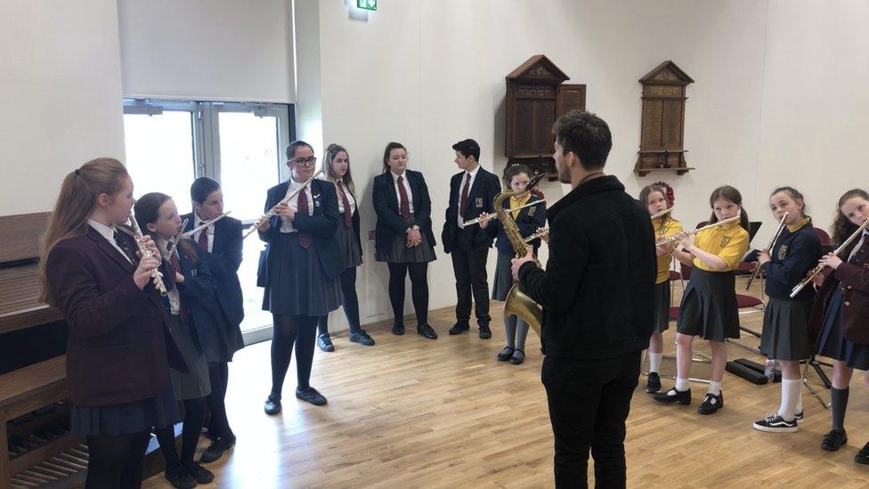 man playing saxophone to children