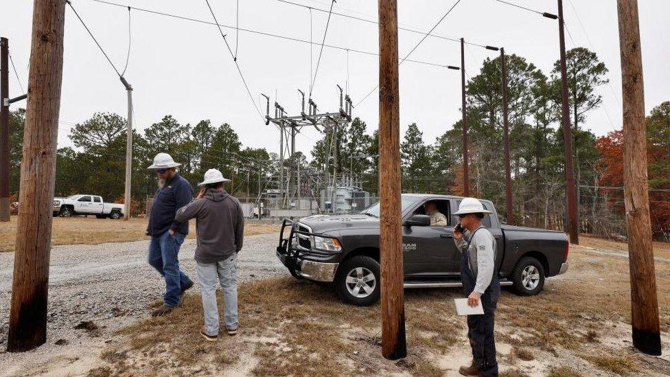 Workers in Moore County gather around a pick-up truck at one of the substations as they plan on how to assess the damage and fix it