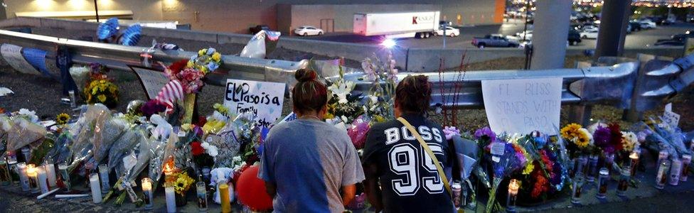 Two women kneel to pray at a memorial at the site of a mass shooting at a Walmart in El Paso, Texas