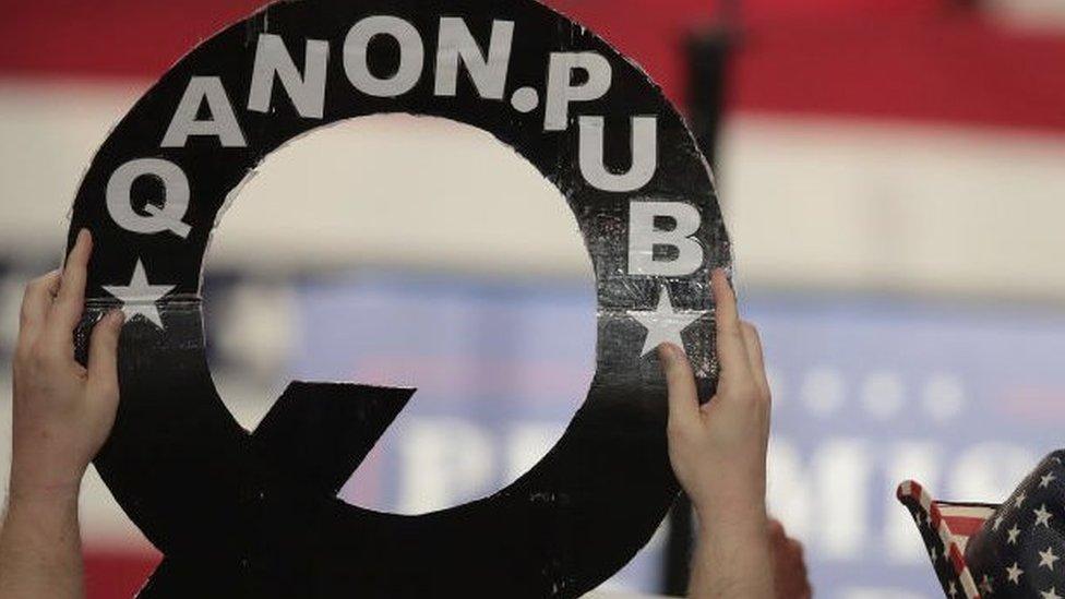 QAnon supporter holds up poster at Trump rally