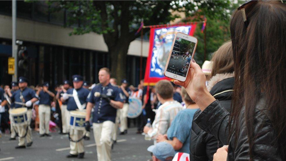 Girl uses phone to film Twelfth of July parade in Belfast