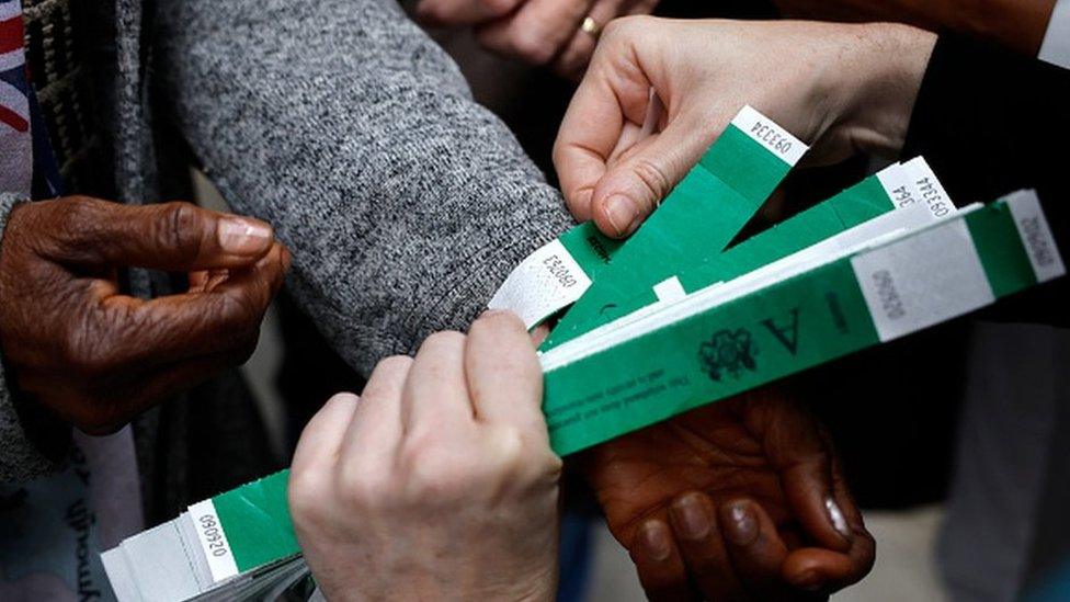 Hand holding three green paper wristbands