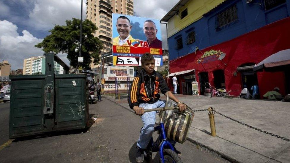 A boy rides his bicycle past a billboard promoting pro-government congressional candidates in Caracas (04 December 2015)