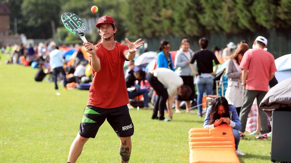 A man plays tennis in the queue