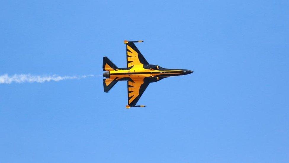 Yellow and black military plane in the sky, tilted vertically