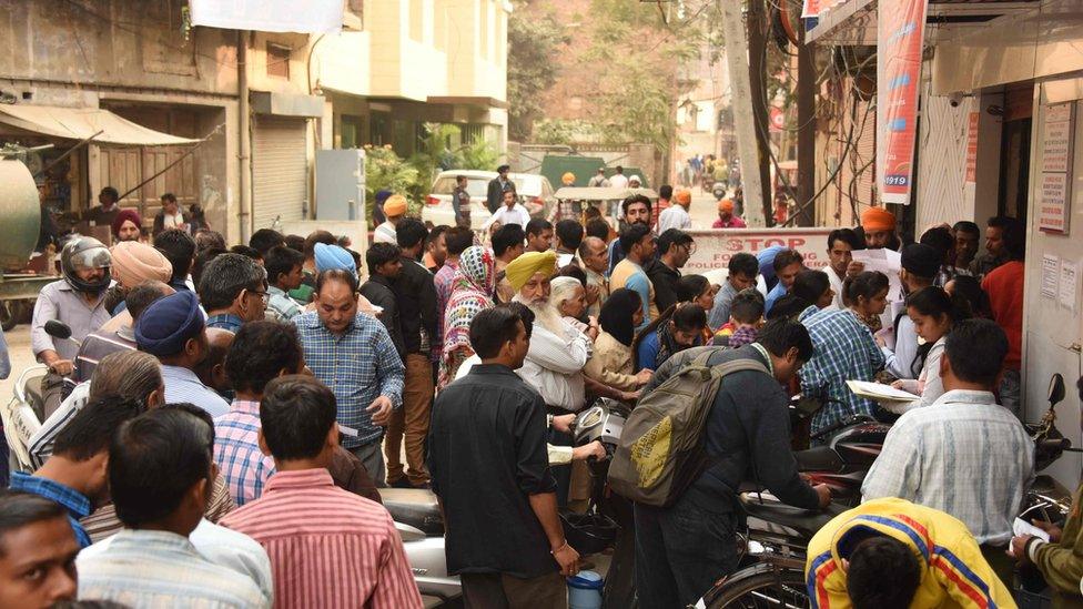 Indian people crowd outside a bank in Amritsar.