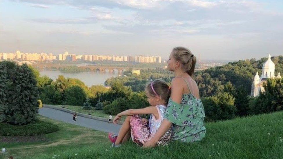 Mariia Nesterchuk with her daughter sitting on a hill in Kyiv