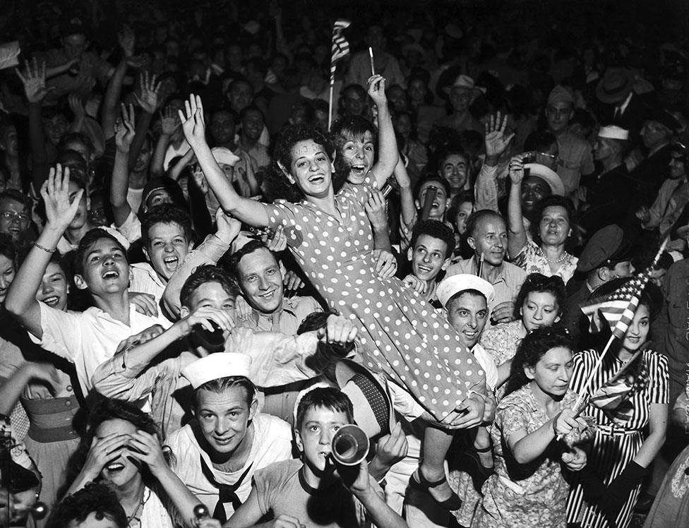 A crowd celebrates and holds a woman in the air