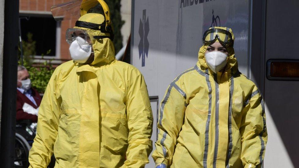 Healthcare workers wearing protective suits stand at the entrance of the Severo Ochoa Hospital in Leganes, near Madrid, on April 03, 2020