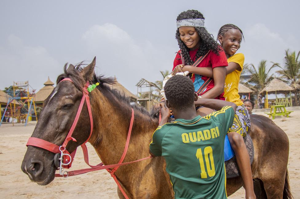 Two people being helped onto a horse