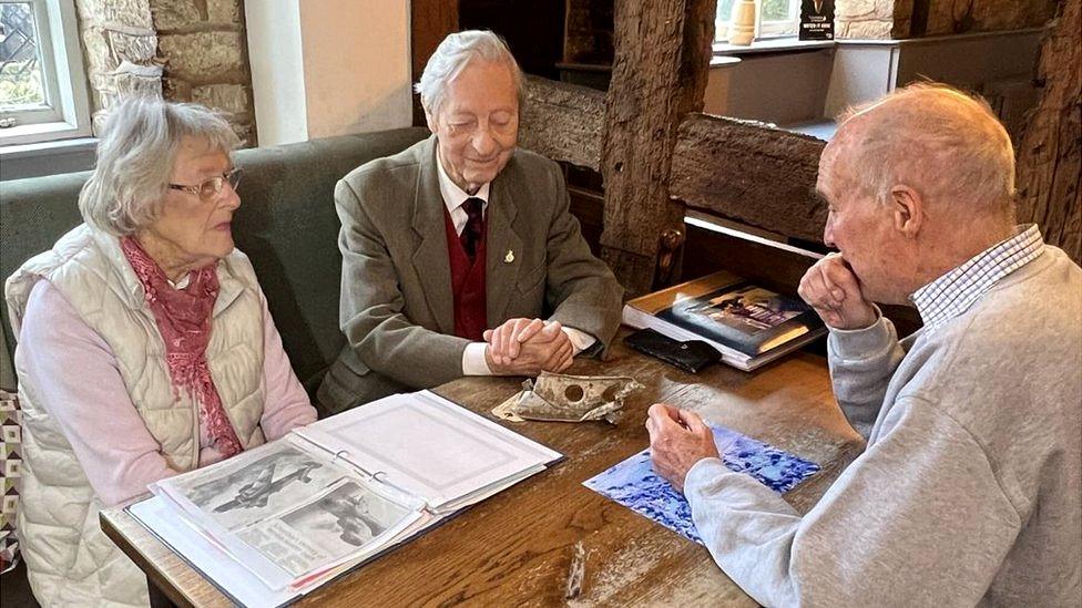 Ms Dembenski and Mr Parkin sitting at a table. In front of them is the fragment from the bomber jet