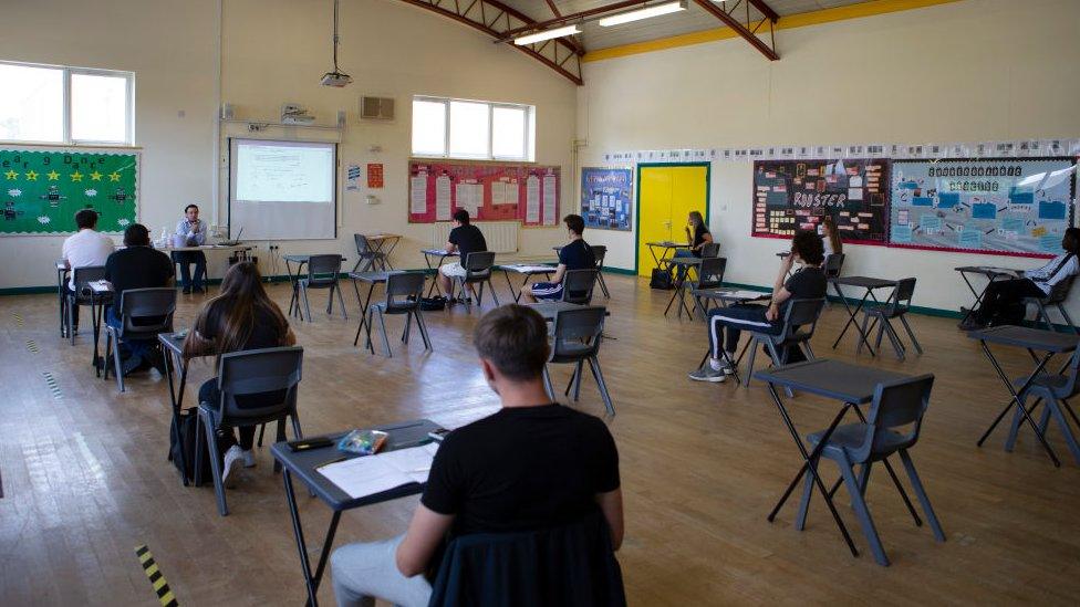 students sitting together in a hall taking exams