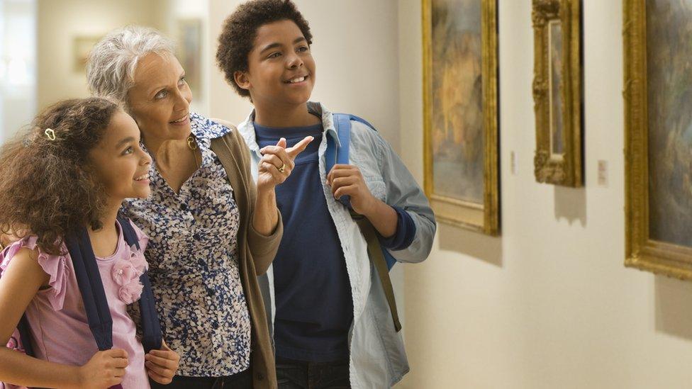 two-children-and-woman-look-at-paintings-in-museum