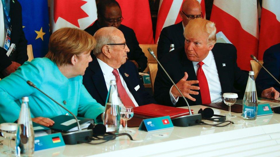 President Donald Trump talks to German Chancellor Angela Merkel (L) and Tunisia's President Beji Caid Essebsi at the G7 Summit on May 27, 2017 in Taormina, Sicily