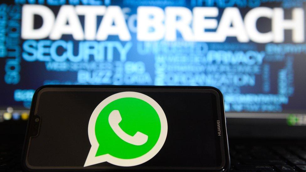 In this photo illustration, the Whatsapp logos is seen on a Huawei smartphone with the word Data breach on a laptop monitor.