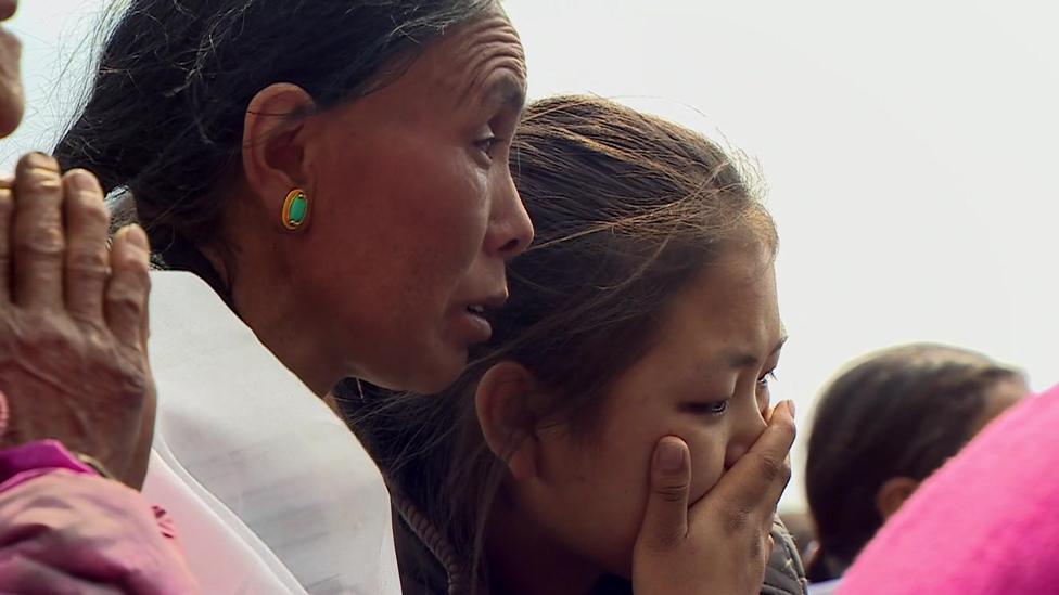 Women praying at a memorial service