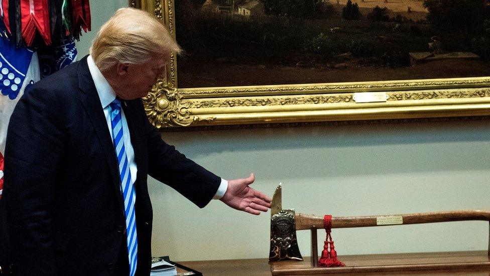 US President Donald Trump (L) looks at an ax presented to him by Atlanta Fire Chief Joel Baker - April 2017