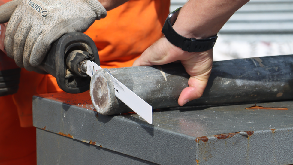 A metal pipe being sawn open