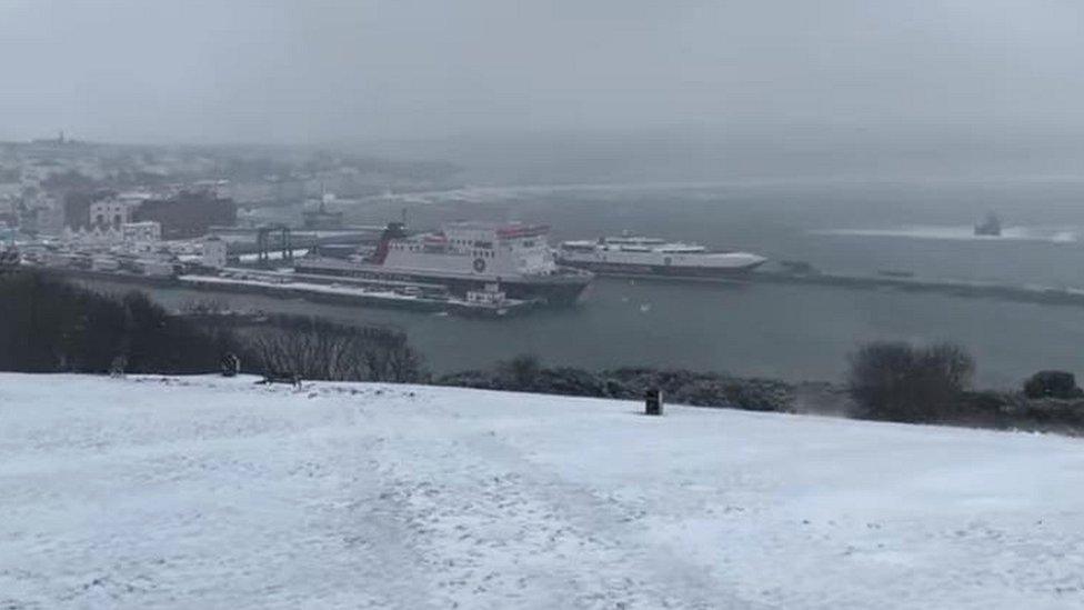 Snow on ground as view looks towards ferry in port